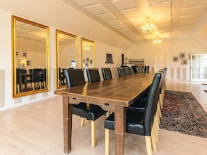 A long dining table with chairs, large mirrors on the walls, and a chandelier.