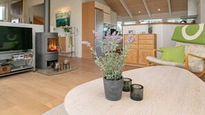 A modern living room with a fireplace, a television, and a round table with candles.