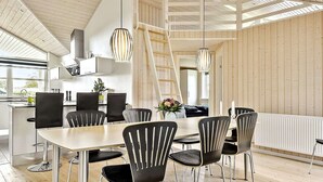 Een moderne keuken met een eethoek, met houten vloeren, zwarte stoelen en hanglampen.