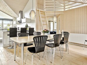 Ein moderner Essbereich mit Holzboden, schwarzen Stühlen und einem zentralen Tisch.