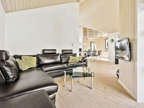A modern living room with a leather sofa, a glass coffee table, and a mounted TV.