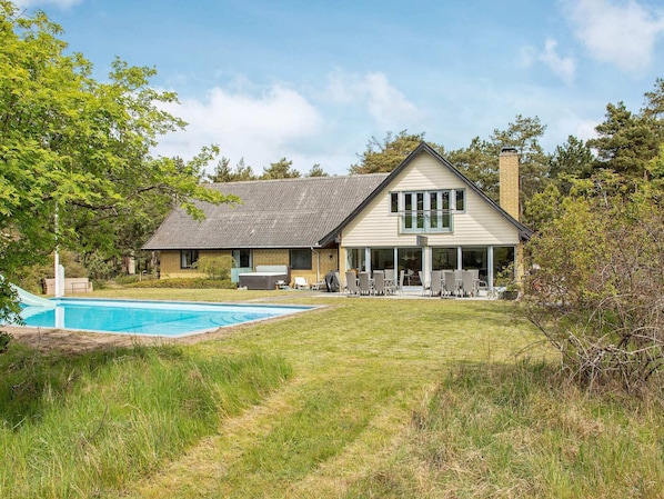 A two-story house with a swimming pool, outdoor seating, and a covered patio.