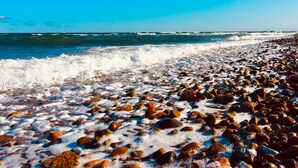 Uma praia rochosa com ondas quebrando na costa.