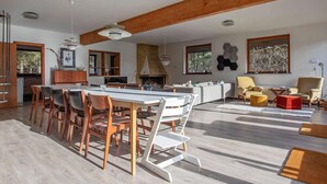 A spacious living area with a dining table, chairs, sofas, and a fireplace.