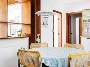 A dining area with a round table, four wicker chairs, a hanging light fixture, and a window with a view. - 14 Person Holiday Home in Sjaellands Odde (Sjællands Odde)