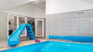 An indoor swimming pool with a blue slide and a ladder.