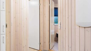 A hallway with wooden walls, a white door, and a tiled floor.