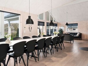 A modern dining area with a long table and chairs, large windows, and a high ceiling. - Holiday Home in Kappeln (Kappeln)