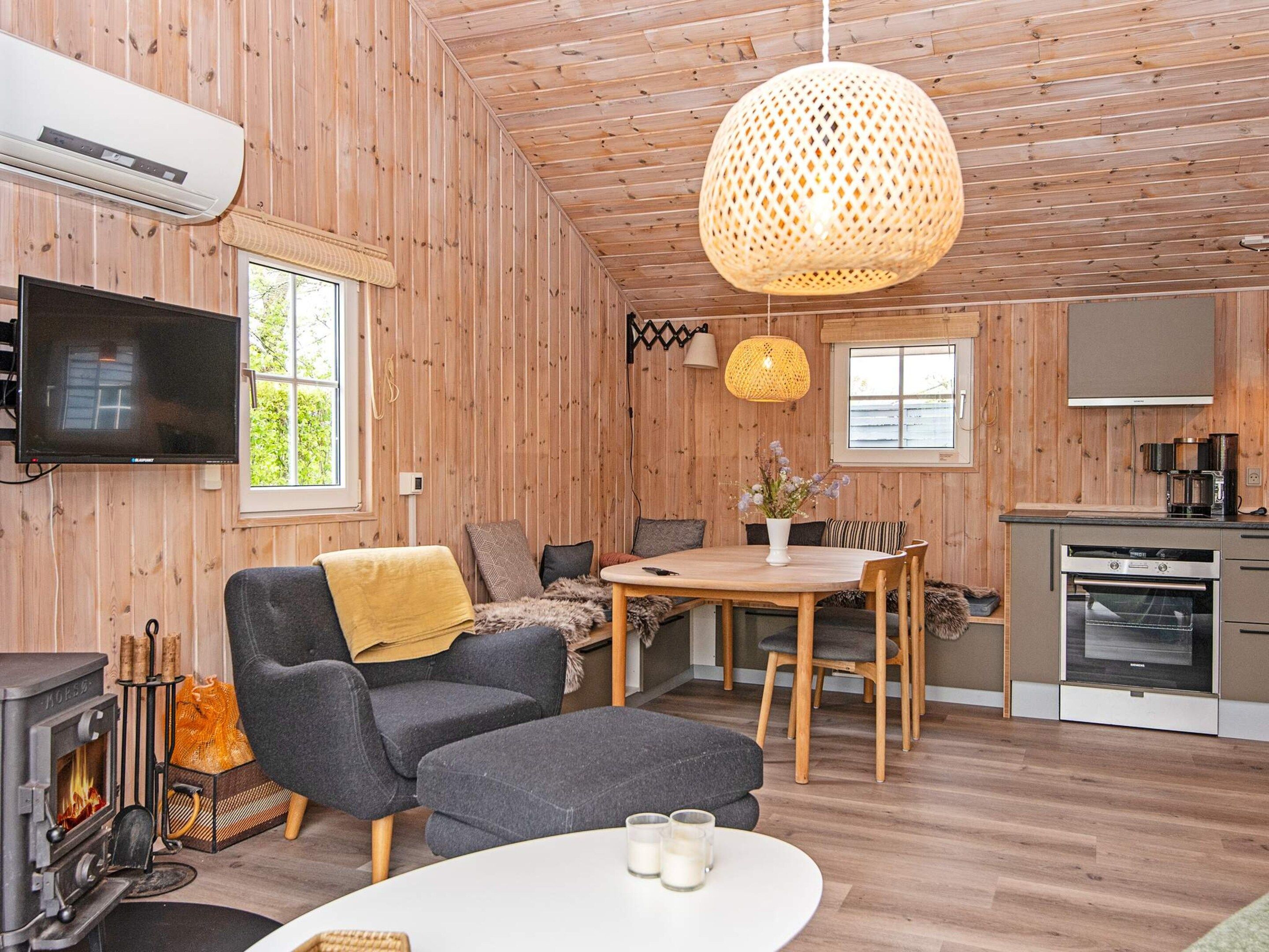 A cozy cabin interior with a sofa, dining table, and a fireplace.