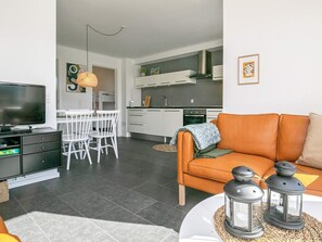 A modern living room with a television, sofa, and decorative lanterns. - Holiday Home in Bogense (Bogense)