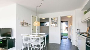 A modern kitchen with a dining area, a TV, and a large window. - Holiday Home in Bogense (Bogense)