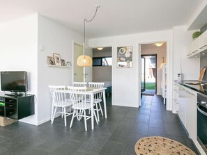 A modern kitchen with a dining area, a TV, and a large window. - Holiday Home in Bogense (Bogense)