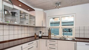 Une cuisine moderne avec des meubles blancs, un four encastré et une fenêtre offrant une belle vue.