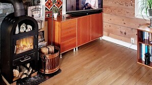 A cozy living room with a wood-burning stove, a television, and a wooden cabinet. - 6 Person Holiday Home in Austrheim (Austrheim)