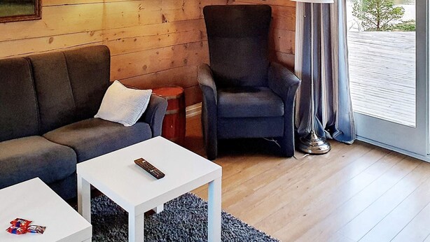 A cozy living room with a sofa, armchair, and a small table. - 6 Person Holiday Home in Austrheim (Austrheim)