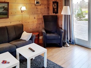 A cozy living room with a sofa, armchair, and a small table. - 6 Person Holiday Home in Austrheim (Austrheim)