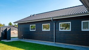 A modern building with a dark exterior, three windows, and a tiled roof. - Holiday Home in Glesborg (Glesborg)