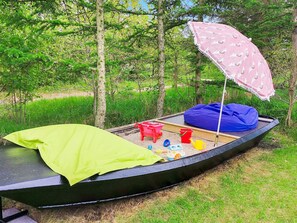 A boat with a green mat, a blue bean bag, a red chair, and a pink umbrella.