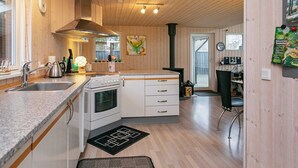 Een moderne keuken met houten wanden, een fornuis, gootsteen en kastjes.