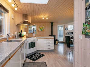 A modern kitchen with wooden walls, a stove, sink, and cabinets.