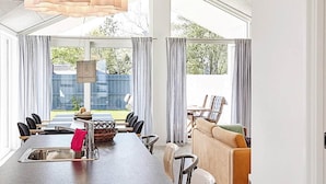 A modern kitchen with a large island, dining area, and seating.
