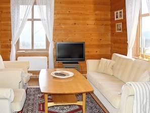 A cozy living room with a wooden interior, a television, a sofa, and a coffee table. - 5 Person Holiday Home in Vassenden (Sunnfjord)