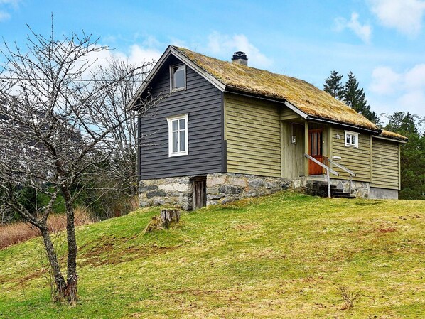 A two-story house with a thatched roof, a stone foundation, and a wooden door. - 5 Person Holiday Home in Vassenden (Sunnfjord)