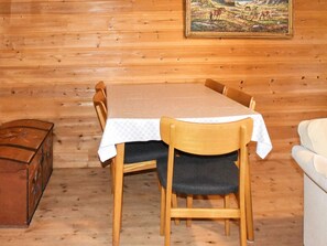A wooden interior with a table and chairs, a painting on the wall, and a suitcase on the floor. - 5 Person Holiday Home in Vassenden (Sunnfjord)