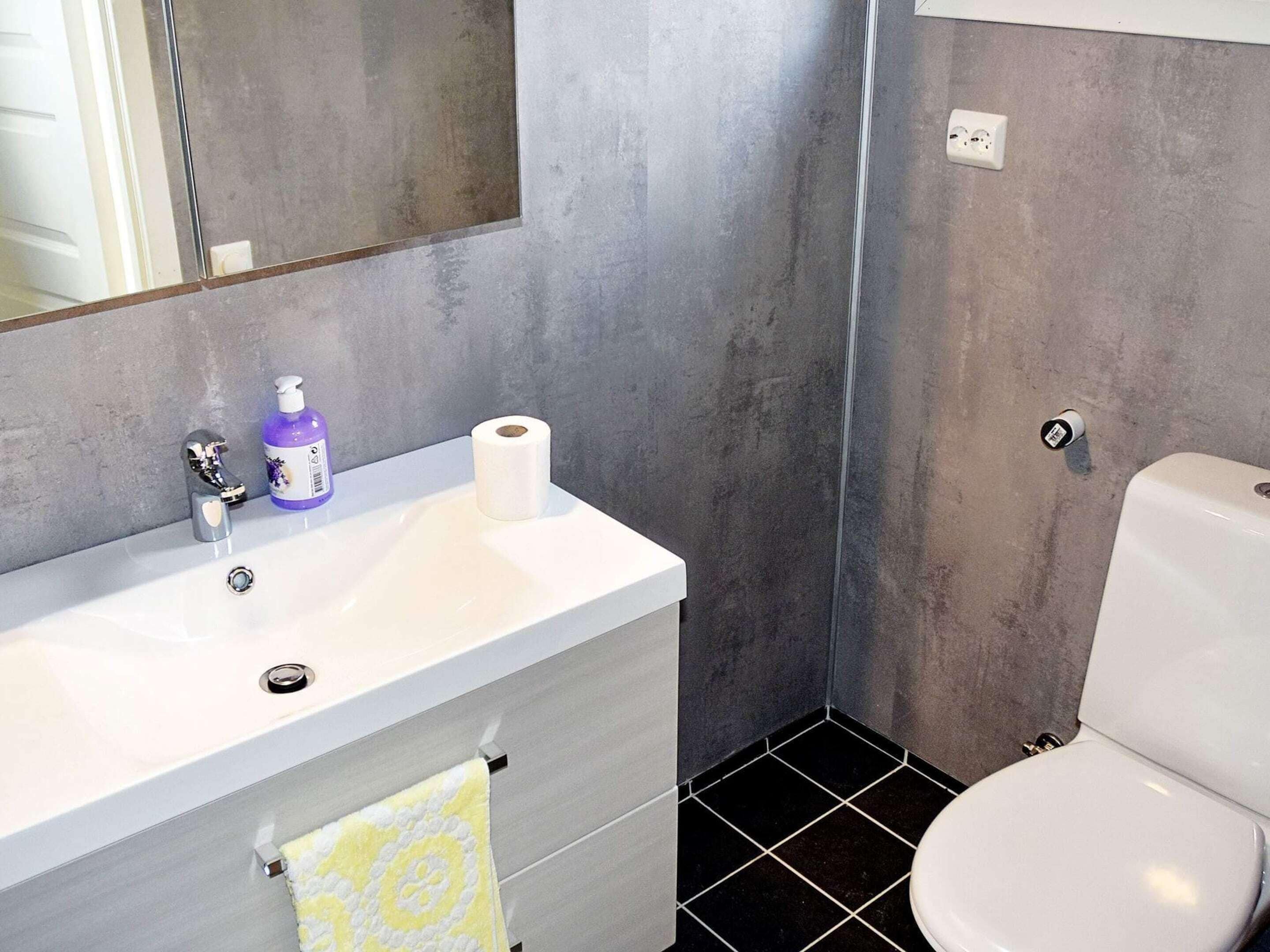 A bathroom with a white sink, a toilet, and a mirror.