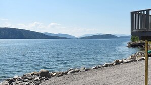 A lakeside view with a wooden dock and rocky shoreline.