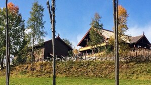 Een landelijke omgeving met traditionele houten gebouwen, een grasveld en een houten omheining.