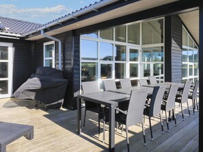 A covered outdoor patio with a dining table and chairs, a sofa, and a grill. - Holiday Home in LÃ¸kken (Lokken)