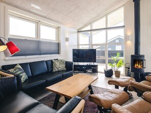 Una sala de estar moderna con sofá, televisión, mesa de centro y chimenea.