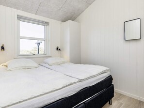 A bedroom with two beds, a window, and a wall-mounted mirror.
