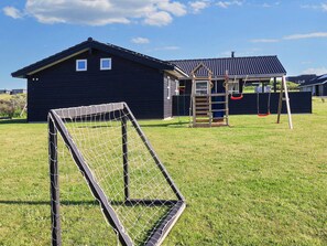 A residential area with a house, a play structure, and a soccer goal.
