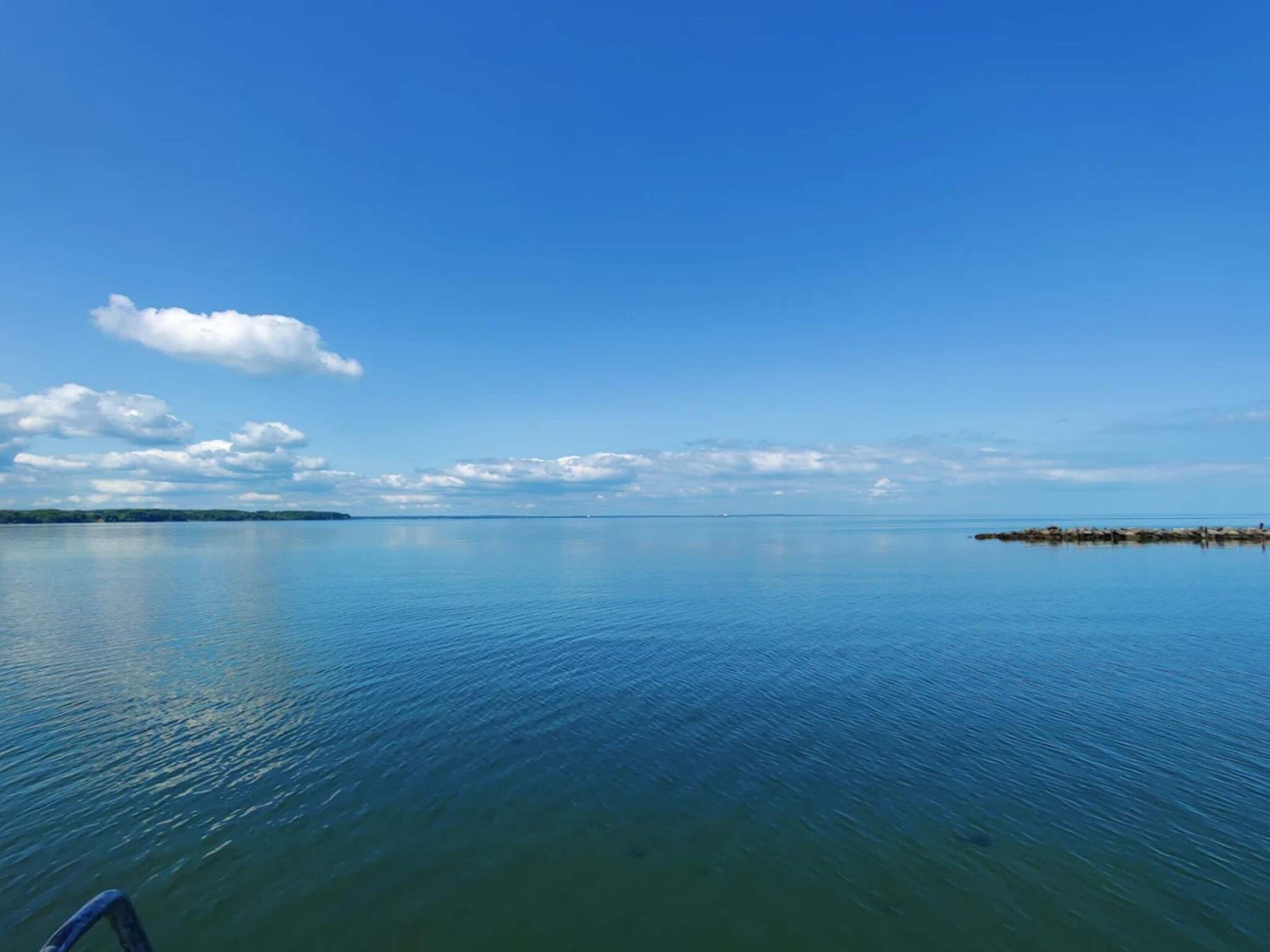 Ruhige Wasserfläche mit klarem Himmel und weiter Landschaft.