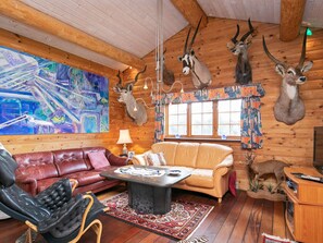 A cozy room with a leather sofa, a coffee table, and a painting on the wall.