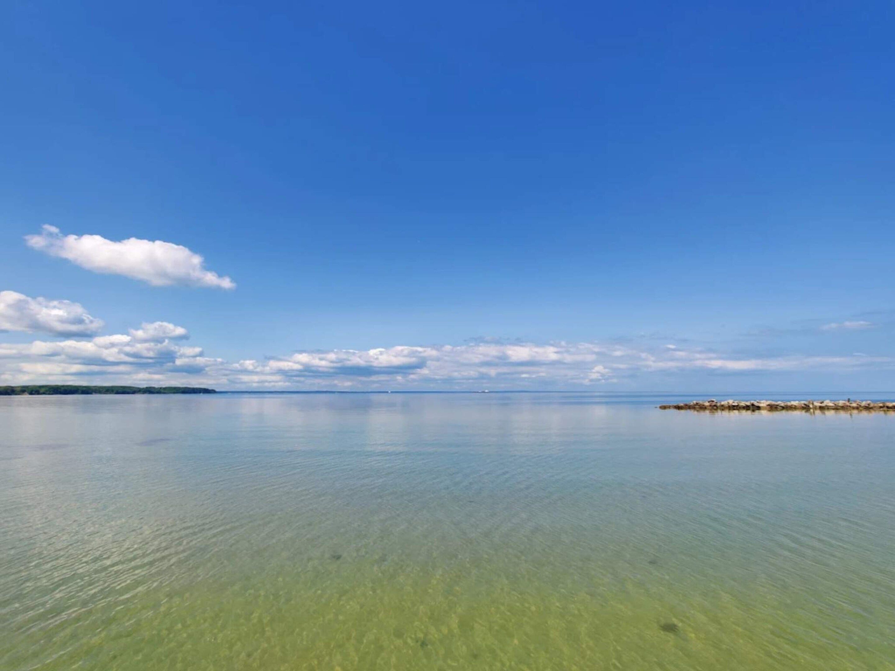 A calm sea with clear water and a distant shoreline.