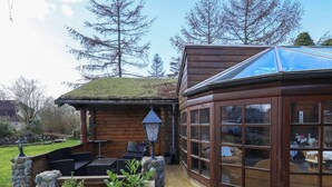 A wooden cabin with a glass conservatory, stone steps, and outdoor seating. - 5 Person Holiday Home in Middelfart (Middelfart)