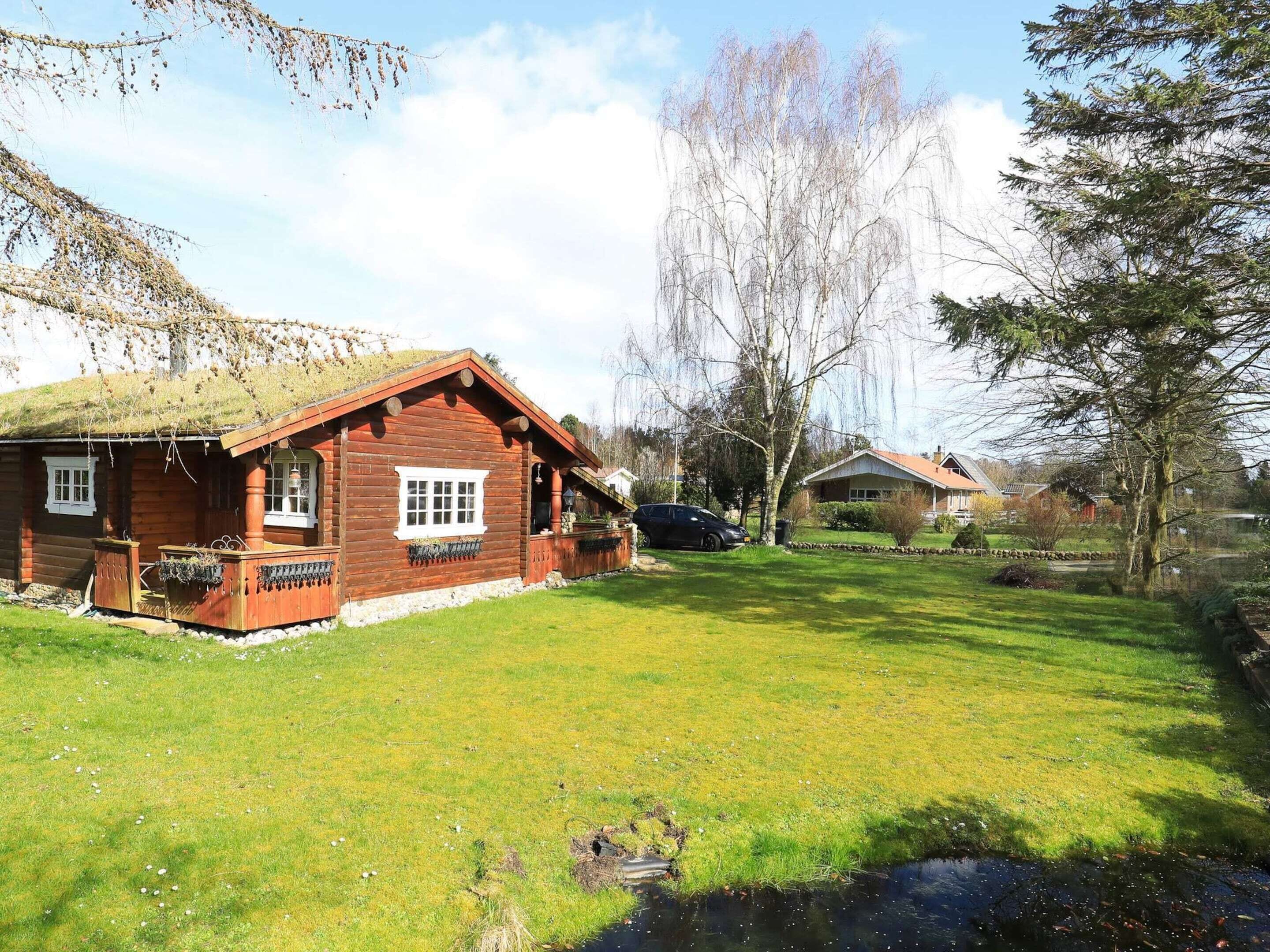 A wooden cabin with a sloped roof, a small porch, and a grassy yard.