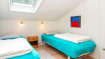 Una habitación con dos camas, un tragaluz, una obra de arte en la pared y una pequeña mesita de noche de madera.