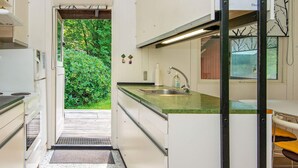 A compact kitchen with a built-in sink, a refrigerator, and a window overlooking a garden. - 5 Person Holiday Home in Ry (Ry)