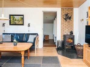 A cozy living room with a sofa, a wooden table, a fireplace, and a television.