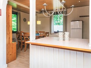 A compact kitchen with a central island, wooden chairs, a dining table, and a refrigerator.