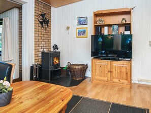 A cozy living room with a fireplace, a television, and a wooden cabinet.