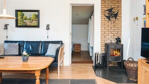 A cozy living room with a sofa, a wooden table, a fireplace, and a painting on the wall.