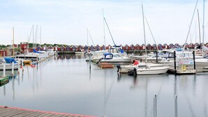 A marina with boats docked, a wooden pier, and red-roofed buildings in the background. - 8 Person Holiday Home in Traslovslage (Träslövsläge)