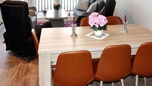 A dining area with a wooden table, four brown chairs, a sofa with cushions, a black chair, and a window with a view. - 4 Star Holiday Home in Vatne (Ålesund)