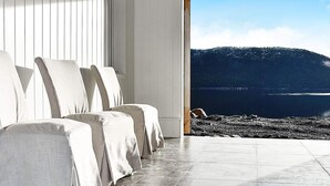A modern room with a large window overlooking a rocky shoreline and a mountain. - 4 Star Holiday Home in Vatne (Ålesund)