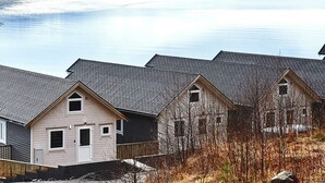 A residential area with houses, a wooden fence, and a body of water in the background. - 4 Star Holiday Home in Vatne (Ålesund)